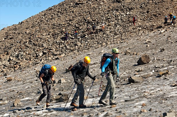 Three mountaineers on the way to the Mont Blanc peak crossing an ice field near the Tete-Rousse mountain hut, Chamonix, France