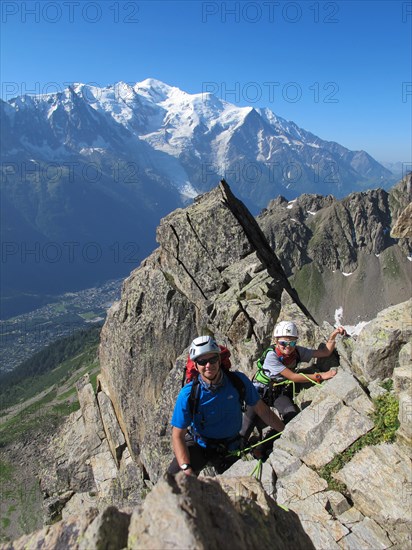 Boy and father rock climbing on a sunny day in the alps.  Mont Blanc is in the background.