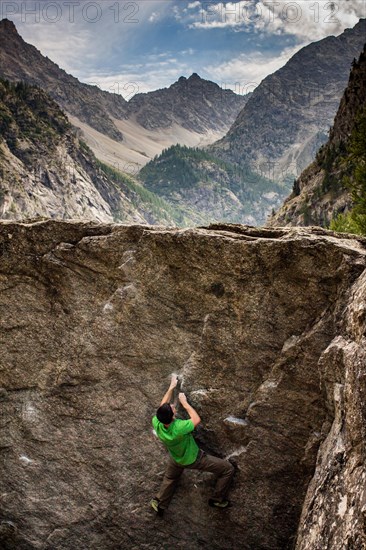 Young man climbs boulders in the Alfroide valley, French Alps