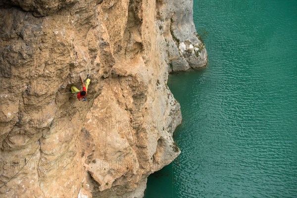 View from above of rock climber climbing cliff on shore, Verdon Gorge, Alpes-de-Haute-Provence, France