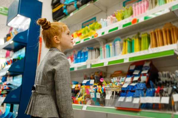 School girl choosing a pencil in stationery store