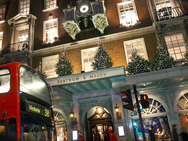 Fortnum & Mason department store at night with typical London red bus in foreground Christmas London UK  2012