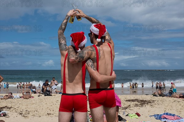 men toasting a merry christmas on Coogee beach, Sydney, New South Wales, Australia