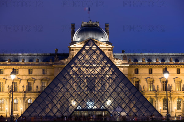 The Louvre Museum illuminated glass pyramid entrance Paris France