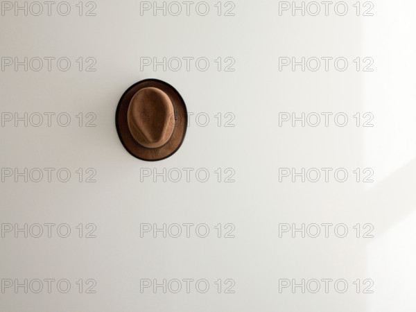 lone brown corduroy hat on white wall.