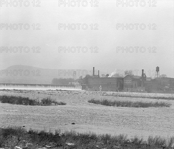 Mt. Holyoke, Massachusetts - Scenes. The dam: The Connecticut River: the old and famous Hampshire bond manufacturing plant, recently bought by its neighbor, Carew Manufacturing. Also an old and independent mill; founder paternalistic enough to build a church which still stands, enough local feeling to employ from South Hadley because on the Hadley side of the River - Carew Manufacturing Company, 1936 , Lewis Hine, 1874 - 1940, was an American photographer, who used his camera as a tool for social reform. US,USA