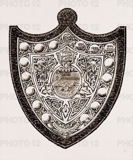 these indicate that the Honourable Artillery have won the shield twice and the Queen's Westminsters once. The Arms of the Honourable Artillery Company appear at the top of the shield, and an inscription below this bears the name of the company as donors. At the base of the shield is a scroll with the inscription, 64 Promoted by the Tadpoles,