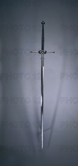 Two-Handed Sword, 1550-1600. Spain, Toledo (?), second half of 16th Century. Steel, wood and leather grip; overall: 167.3 cm (65 7/8 in.); blade: 126 cm (49 5/8 in.); quillions: 31.8 cm (12 1/2 in.); grip: 40 cm (15 3/4 in.); ricasso: 17.2 cm (6 3/4 in.).