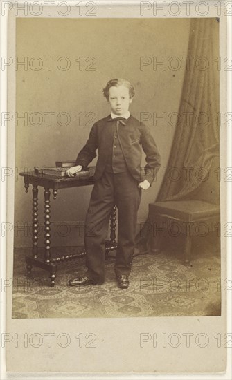 little boy in suit standing at a table with books on top; Joseph Brown, British, active 1860s, about 1869; Albumen silver print