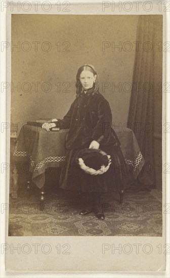 young girl in curls, standing, holding a hat, resting her other arm on a table with books on top; Joseph Brown, British, active