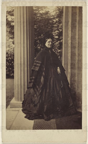 elderly woman standing outside near column at house entrance; J.G. & E.G. Short, British, 1865 - 1875; Albumen silver print