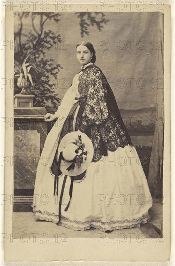 woman wearing a long dress with a dark shawl, standing, holding a bonnet; W. Hilliger, German, active Bad Homburg, Germany 1860s