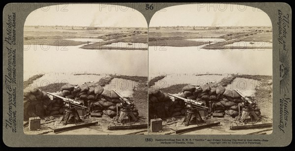 Destructive guns from H.M.S. 'Terrible' and distant burning city fired by their shells, Ricalton, James, Underwood and Underwood