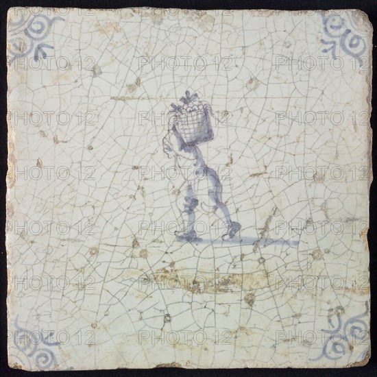 Occupation tile, blue with man crumbling with basket on the back, corner motif ox's head, wall tile tile sculpture ceramic