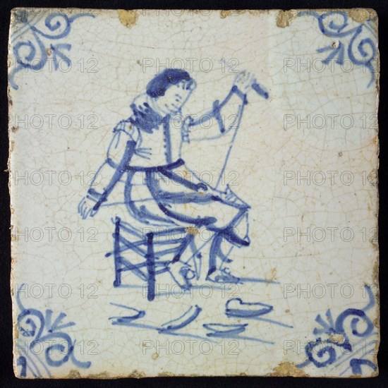 Occupation tile, blue with seated cobbler, corner motif of ox's head, wall tile tile sculpture ceramic earthenware glaze wood