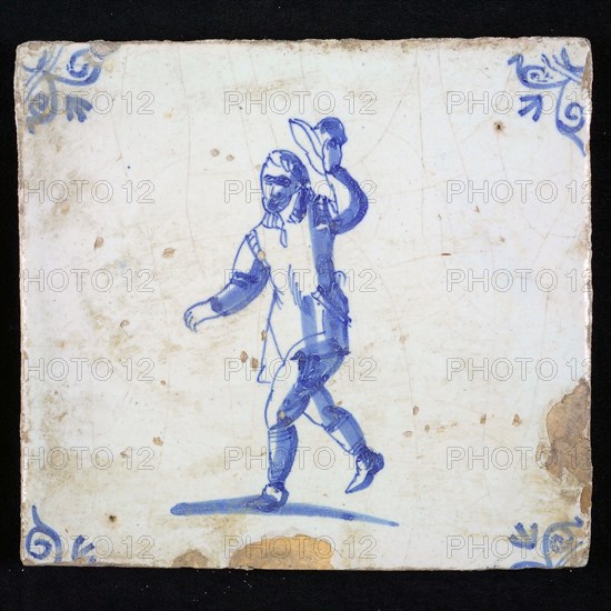 Figure tile, blue with running man with his hat taking off as greeting, corner motif of ox's head, wall tile tile sculpture