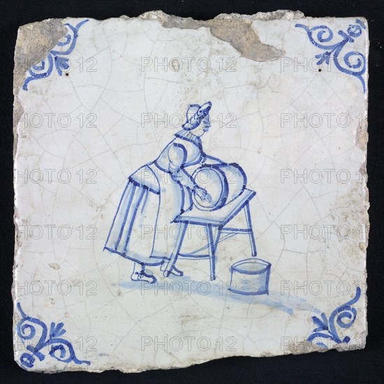 Figure tile, blue with woman cleaning barrel, on table, corner motif oxen head, wall tile tile sculpture ceramic earthenware