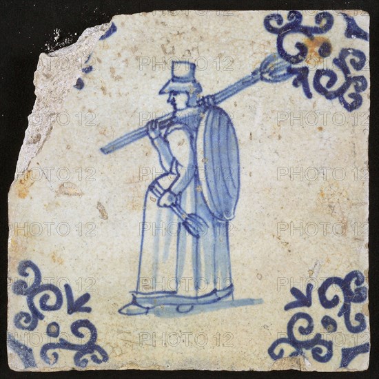 Occupation tile, blue with woman with pitchfork over the shoulder and flat basket On the back, corner motif voluut, wall tile