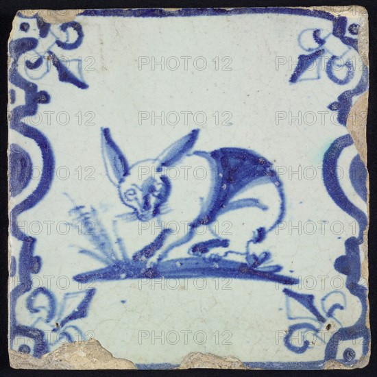Animal tile, standing hare to the left on ground between balusters, in blue on white, corner pattern French lily, wall tile