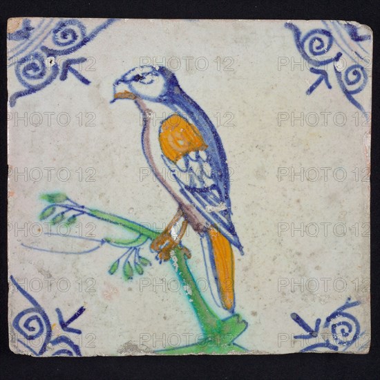 Animal tile, bird on branch to the left in orange, green, purple and blue on white, corner pattern ossenkop, wall tile