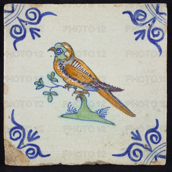 Animal tile, bird on branch to the left in orange, green, purple and blue on white, corner pattern ossenkop, wall tile