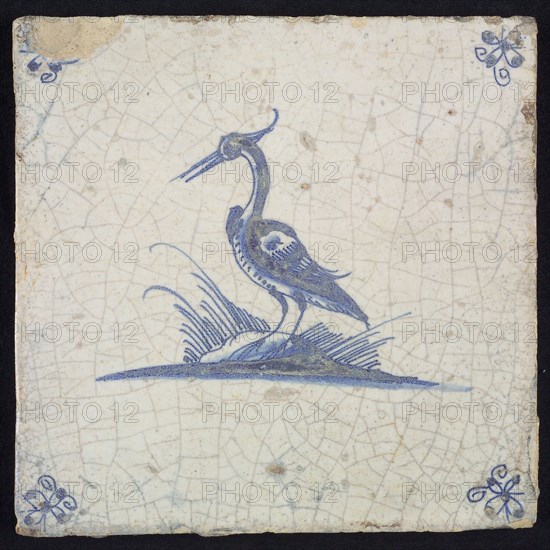 Animal tile, standing heron to the left on ground, in blue on white, corner motif spider, wall tile tile sculpture ceramic