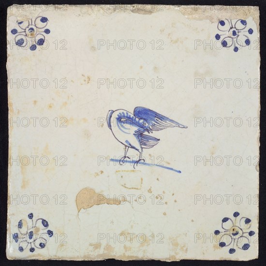 Animal tile, standing bird with curved head under the wing to the left, in purple and blue on white, corner motif spider, wall