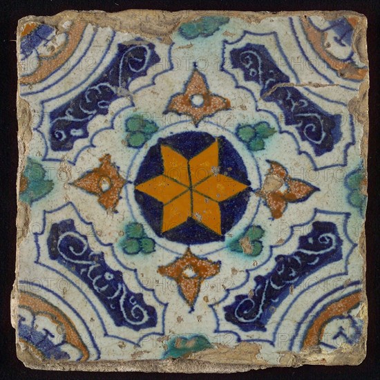 Tile, blue, green, brown and yellow on white, central an orange star in circle, sgraffito surfaces, corner motif quarter rosette