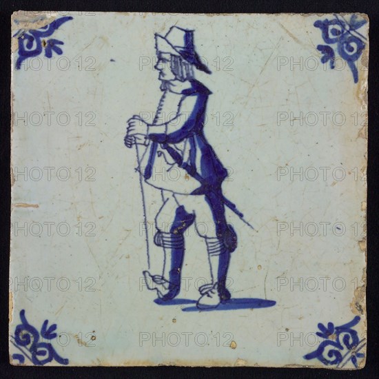 White tile with blue warrior with sword, stick and hat; corner pattern ox head, wall tile tile sculpture ceramic earthenware