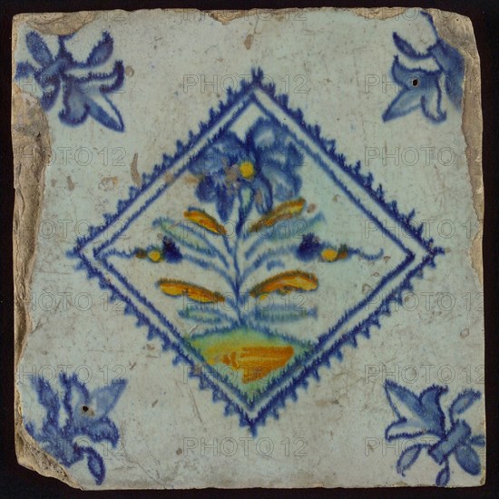 Tile, flower on spot in yellow, orange, green and blue on white, inside serrated square, corner pattern french lily, wall tile