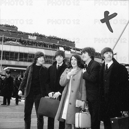 The Beatles leave London Airport bound for the Bahamas to commence filming on their second movie, "Help!", 22 February 1965. Lefto right:John Lennon, Paul McCartney, George Harrison and Ringo Starr.   With them is co-star, Eleanor Bron.