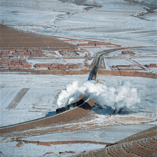 A steam train running across snow-covered land of Northeast China