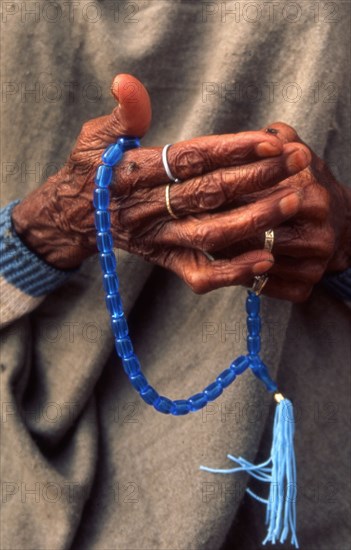 Une femme récitant son chapelet (Tasbih) devant une mosquée, au Pakistan