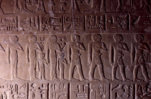 Procession of men and women with child on a block carved with the name of Snefru