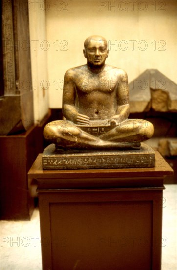 Cross-legged scribe holding a papyrus scroll