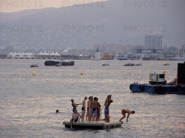 CoteAzur061 Cannes, la Croisette, la baie et les plages, Le Suquet et le vieux port, le Palais des festivals, baigneurs et plongeoir, au soleil couchant (été)