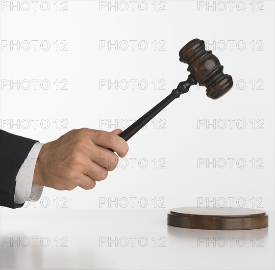 Close up studio shot of judge's hand with gavel.