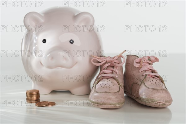 Studio shot of baby shoes and piggy bank.