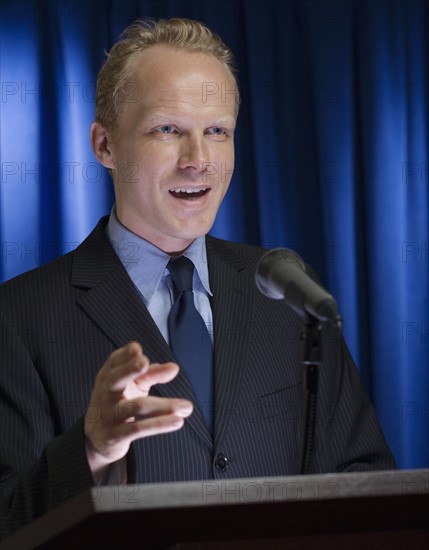 Close up of businessman speaking at podium.