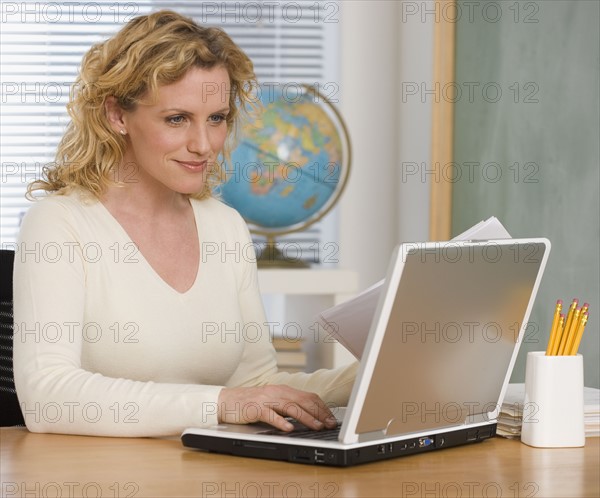 Female teacher typing on laptop.