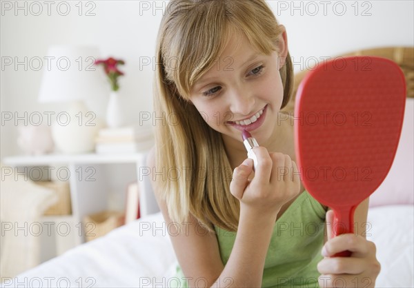 Teenaged girl applying lipstick.