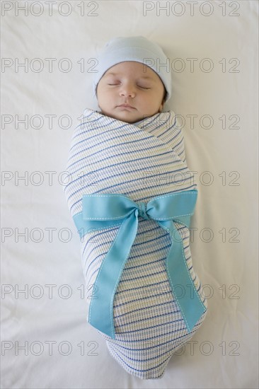 Baby wrapped in blanket with bow.