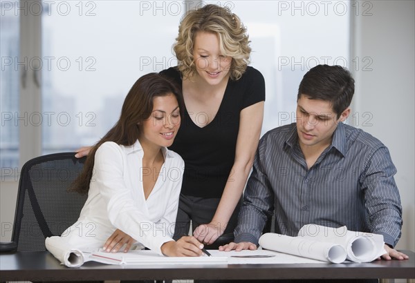 Multi-ethnic businesspeople looking at blueprints.