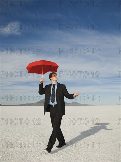 Businessman walking with umbrella, Salt Flats, Utah, United States. Date : 2007