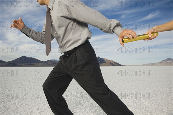 Businessman taking baton in relay race, Salt Flats, Utah, United States. Date : 2007