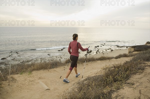 Hispanic woman pole walking along coast in California, United States. Date : 2007