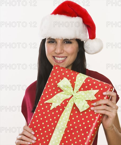 Woman in Santa Claus hat holding gift.