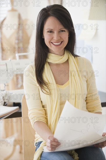 Female clothing designer holding drawings.