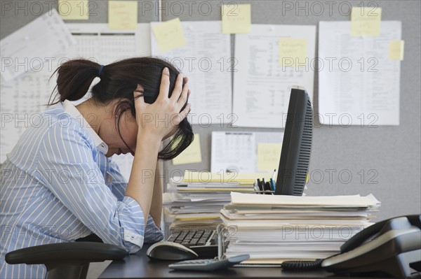 Businesswoman with head in hands.