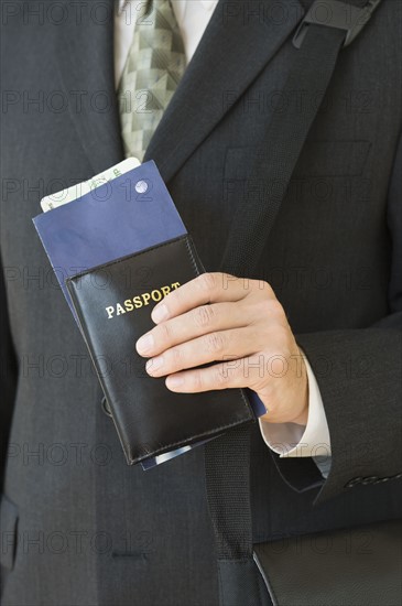 Businessman holding passport and airplane ticket.